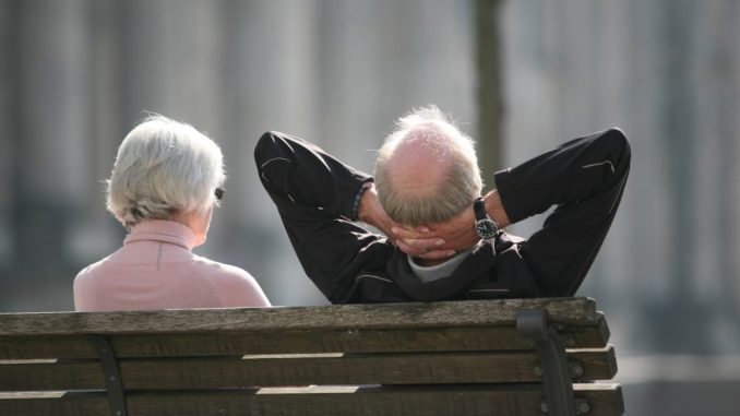 Ein Rentnerpaar sitzt auf einer Bank und sonnt sich. Foto: Stephan Scheuer/Archiv