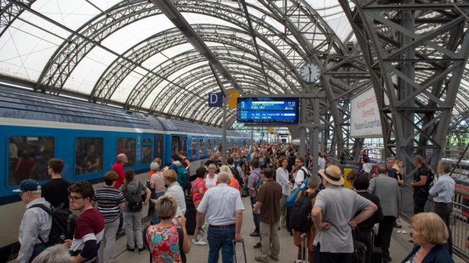 Zugreisende warten auf einem Gleis im Hauptbahnhof in Dresden. Foto: Arno Burgi